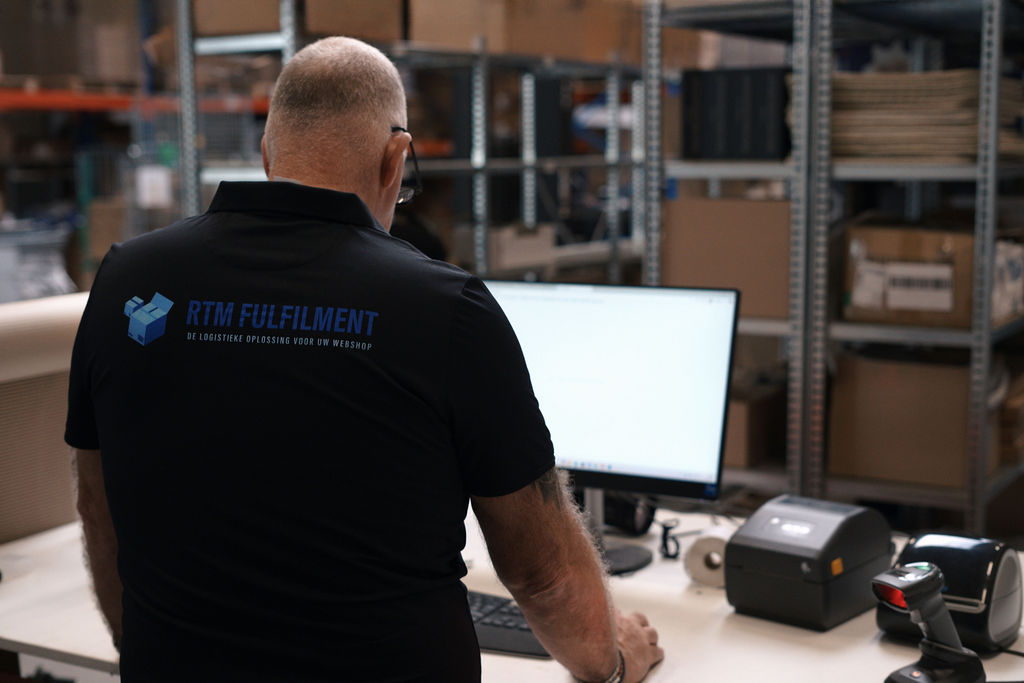 Medewerker van RTM Fulfilment aan de inpaktafel met labelprinter